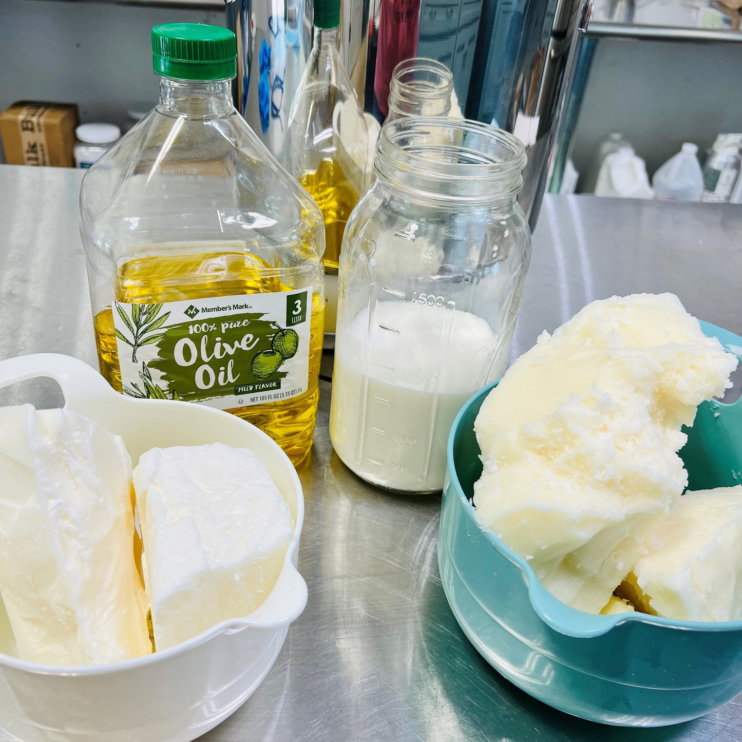 Bowl with whipped cream, bottles of olive oil and milk on a metal surface